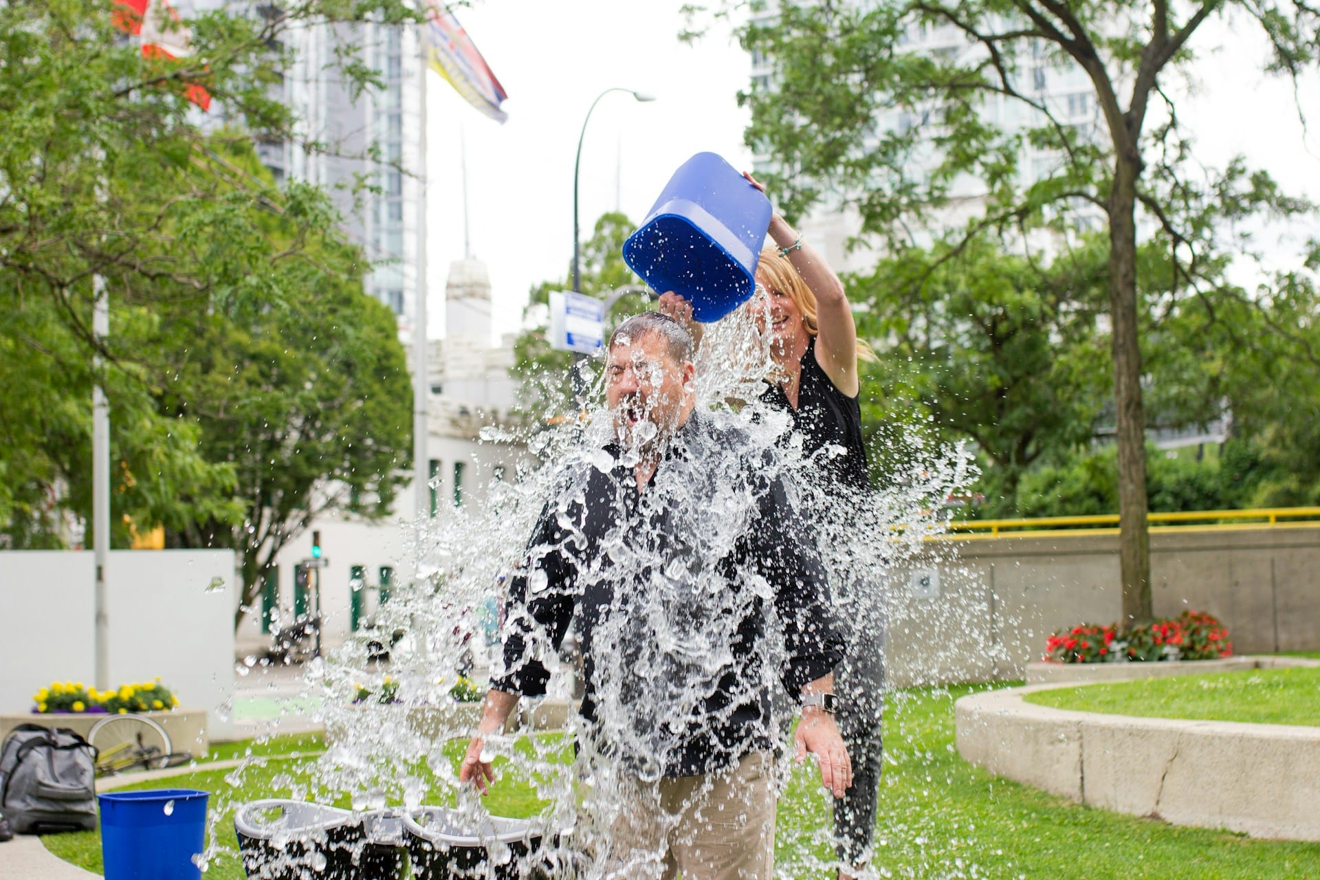 employee-fundraising Woman pours bucket of water over man outdoors